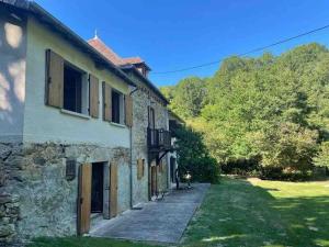 uma casa de pedra com uma passagem ao lado de um quintal em Ancient Mill with Beautiful Lake and Streams em Les Riffes