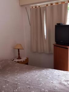 1 dormitorio con 1 cama, TV y ventana en Los paraisos en Mina Clavero