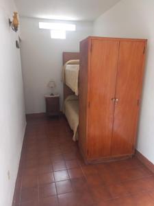 1 dormitorio pequeño con 1 cama y armario de madera en Los paraisos en Mina Clavero