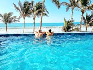 two men in a swimming pool next to the beach at Condominio, Las Pocitas de Máncora- Deluxe in Máncora