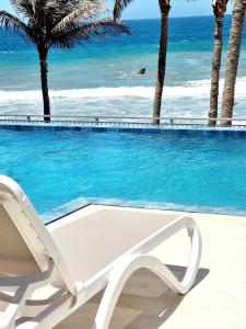 une chaise longue blanche à côté d'une piscine donnant sur l'océan dans l'établissement Condominio, Las Pocitas de Máncora- Deluxe, à Máncora
