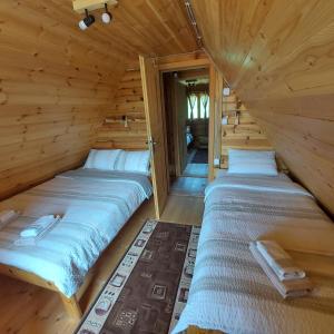 two beds in a log cabin with a doorway at Drveni raj Uvac in Sjenica +65 photos