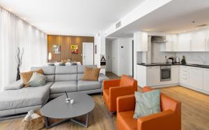 een woonkamer met een bank en stoelen en een keuken bij Beach Front Dream Penthouse - pool & gym & parking in Herzliyya B