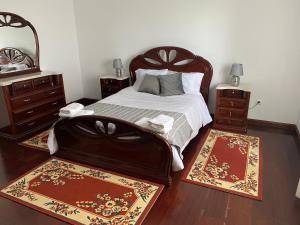 a bedroom with a bed with two night stands and two rugs at Green Tropical House in Ponta Delgada