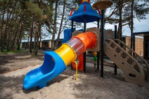 um parque infantil com um escorrega colorido num parque em Darłowo Beach Houses em Darlowko