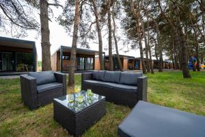 dwa wiklinowe kanapy i stoły w parku z drzewami w obiekcie Darłowo Beach Houses w Darłówku