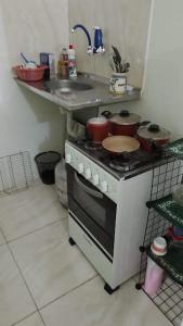 uma cozinha com um fogão e um lavatório com panelas e frigideiras em Espaço interno em Salvador