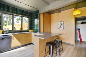 a kitchen with green tiled walls and a counter with stools at Beachfront Bach - Christchurch Holiday Homes in Christchurch