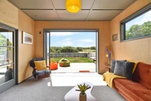 a living room with a couch and a sliding glass door at Beachfront Bach - Christchurch Holiday Homes in Christchurch