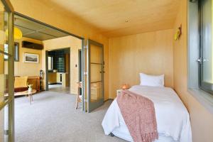 a bedroom with a bed and a sliding glass door at Beachfront Bach - Christchurch Holiday Homes in Christchurch