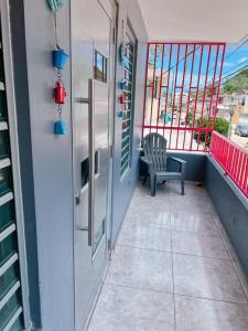 einen Balkon eines Hauses mit einem Stuhl und einem Fenster in der Unterkunft Orsini Beach Apartment in Aguadilla