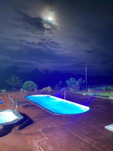 una gran piscina azul por la noche con la luna en Casa de campo completa! Chácara Magnífica!, en Caldas Novas