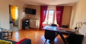 uma sala de estar com uma mesa de jantar e cortinas vermelhas em Le Bienvenue à Colmar, parking gratuit & balcon em Colmar