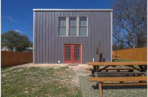 um pequeno barracão com uma porta vermelha e um banco em Gorgeous Guesthouse Near Amazing Downtown em San Antonio