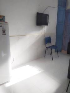 a room with a chair and a television on a wall at Hostel da Residencia in Salvador