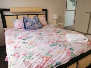 1 cama con edredón y almohadas rosas de flores en Melbourne Lakes warm house, en Melbourne