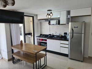 a kitchen with a wooden table and a refrigerator at Apartamento novo em Caiobá in Matinhos