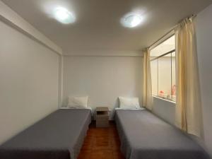 two beds in a room with a window at Hostal Sotillo in Ilo