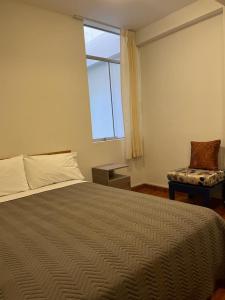 a bedroom with a bed and a window and a chair at Hostal Sotillo in Ilo