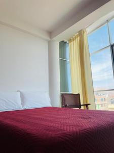 1 dormitorio con 1 cama con manta roja y ventana en Hostal Sotillo, en Ilo