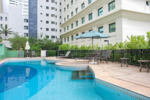 a swimming pool with tables and chairs and a building at Hotel Luxuoso na Paulista in Sao Paulo