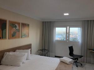 1 dormitorio con 1 cama, 1 silla y 1 ventana en Flat Ponta Negra, en Natal
