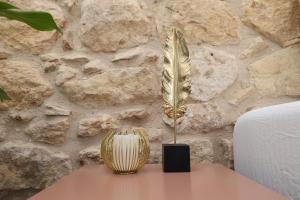 a feather vase on a table next to a stone wall at Helios Boutique by La Finca Hotels in Beer Sheva