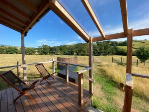 a deck with two chairs and a bench on a field at Dôl Swynol Glamping Luxury cabin with outdoor bath in Aberystwyth