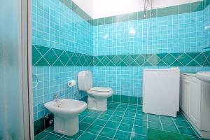 a blue tiled bathroom with a toilet and a sink at Casa Ginevra in Santa Teresa Gallura +25 photos