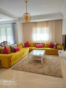 a living room with a yellow couch and a coffee table at Appartement Jawharat Mogador in Essaouira