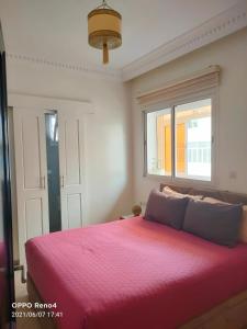 a bedroom with a pink bed with a window at Appartement Jawharat Mogador in Essaouira