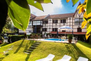 a house with a swimming pool in front of it at Hotel Steinhausen Colonial in Blumenau