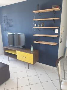 a living room with a tv and a desk and shelf at Apartamentos Natal in Natal