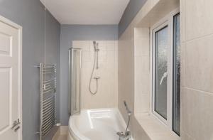 a bathroom with a white tub and a shower at Tibbersley House Billingham With Parking in Stockton-on-Tees