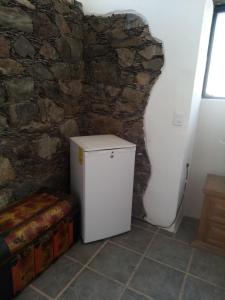 a small refrigerator in a room with a stone wall at Villas de Alcazaba in Real de Catorce