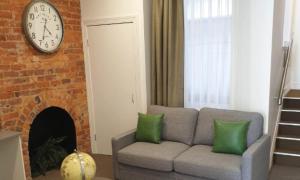 a living room with a couch and a clock on a brick wall at The Hotel Shamrock in Bendigo