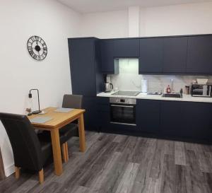 een keuken met blauwe kasten en een houten tafel met stoelen bij Contemporary 1 Bed Apartment, In Central Buxton in Buxton