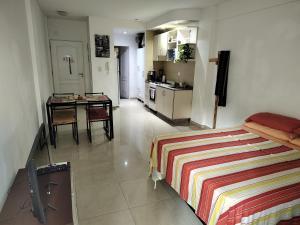 1 dormitorio con cama, mesa y cocina en Departamento Fines de Semana y Feriados para 1 o 2 personas en Buenos Aires