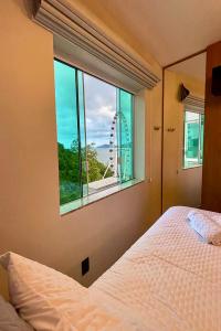 a bedroom with a bed and a large window at Studio de frente para o mar em Balneário Camboriú in Balneário Camboriú