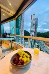 un bol de fruta en una mesa con un vaso de zumo de naranja en Studio de frente para o mar em Balneário Camboriú, en Balneário Camboriú