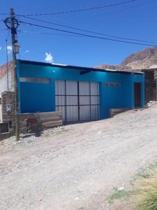 un edificio azul al lado de un camino de tierra en Hosteria M.G en Tilcara