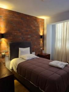 um quarto com uma cama grande e uma parede de tijolos em Hotel Central Pacasmayo em Pacasmayo