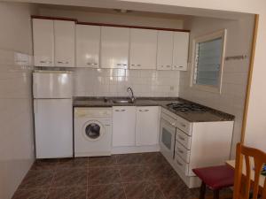 cocina con armarios blancos, lavadora y secadora en CYE 5 Rentalmar, en La Pineda