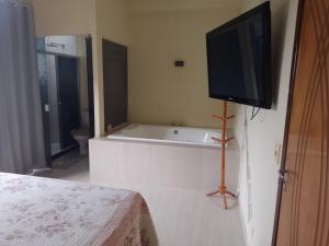 um quarto com uma banheira e uma televisão na parede em CASA GRIEBELER no Rio de Janeiro