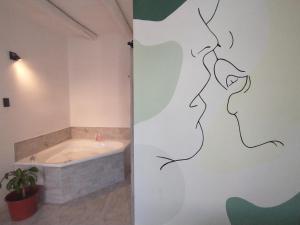 a bathroom with a bath tub and a bathroom with a painting on the wall at Sierras Alojamiento in Mina Clavero