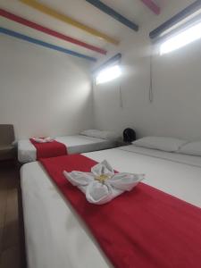 a room with three beds with red and white sheets at Hotel Café Color in Armenia