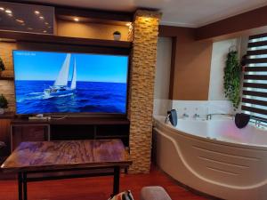ein Badezimmer mit einer Badewanne und einem TV mit einem Segelboot. in der Unterkunft PULLMAN HOTEL in Juliaca