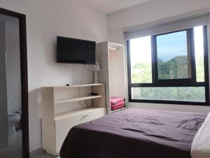 1 dormitorio con 1 cama, TV y ventana en Departamento XIBI en San Salvador de Jujuy