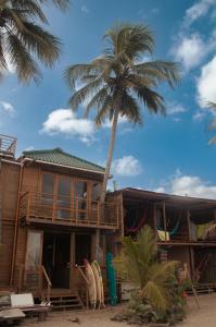 uma casa na praia com uma palmeira em Mendihuaca Surf Camp em Guachaca
