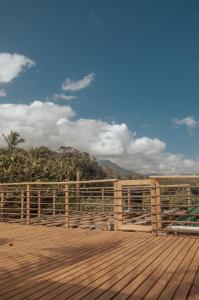una terraza de madera con una valla y montañas en el fondo en Mendihuaca Surf Camp en Guachaca